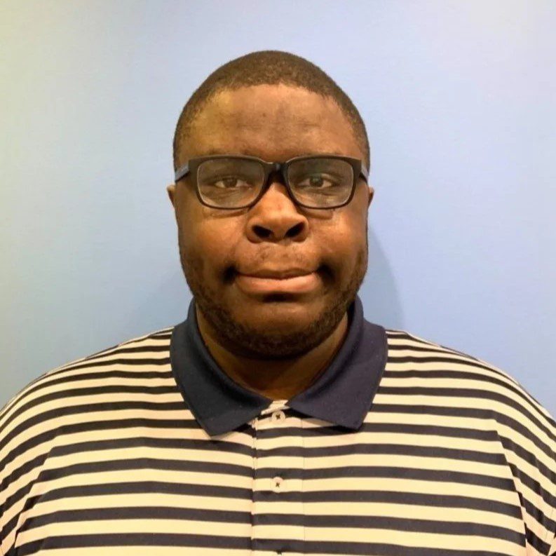 Young Black man with glasses wearing a striped collared shirt