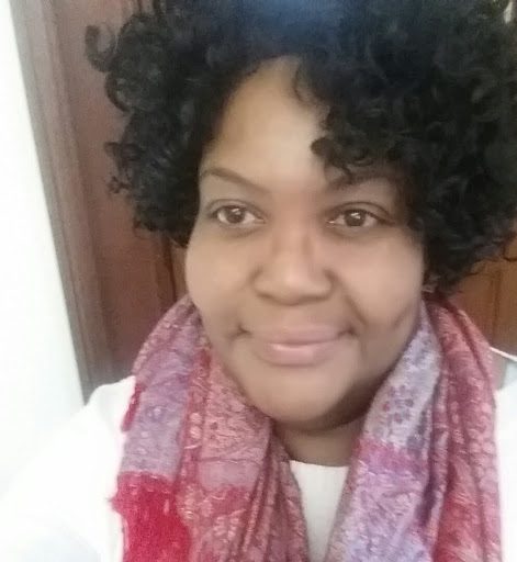 Black woman with curly hair wearing a red scarf around her neck and a white shirt