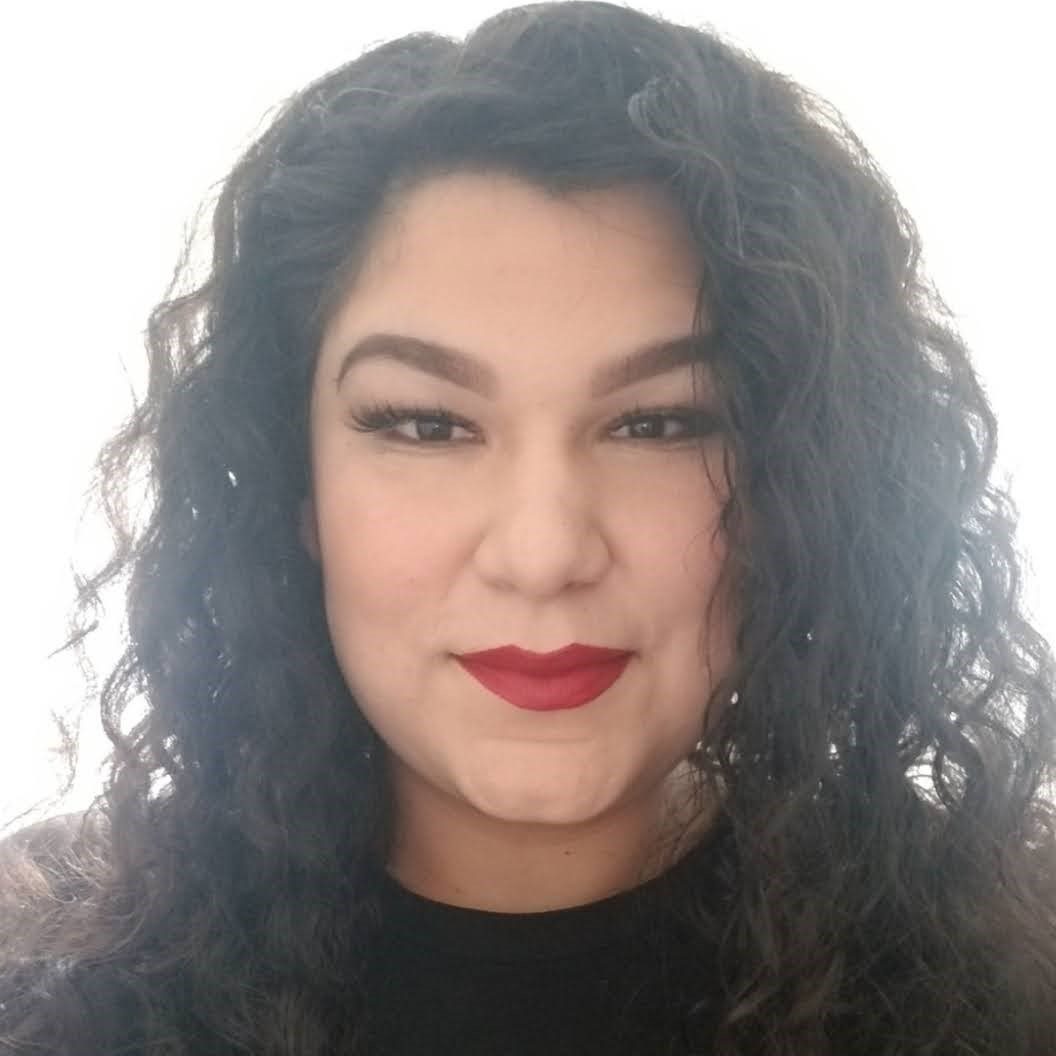 Native american woman with curly dark hair and painted red lips wearing a black shirt